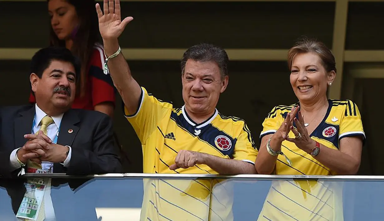 Sesekali, Presiden Kolombia, Juan Manuel Santos (kiri) bersama sang istri, Maria Clemencia, melambaikan tangan saat menyaksikan langsung laga Los Cafeteros kontra Pantai Gading di Stadion National Mane Garrincha, Brasil, (19/6/2014).(REUTERS/Paul Hanna)