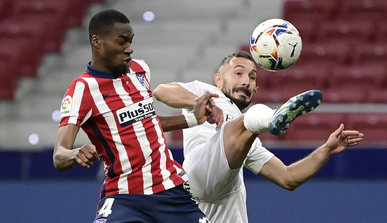 Gelandang Atletico Madrid, Geoffrey Kondogbia (kiri) berebut bola dengan gelandang SD Huesca, David Ferreiro dalam laga lanjutan Liga Spanyol 2020/2021 pekan ke-32 di Wanda Metropolitano Stadium, Madrid, Kamis (22/4/2021). Atletico menang 2-0 atas SD Huesca. (AFP/Javier Soriano)