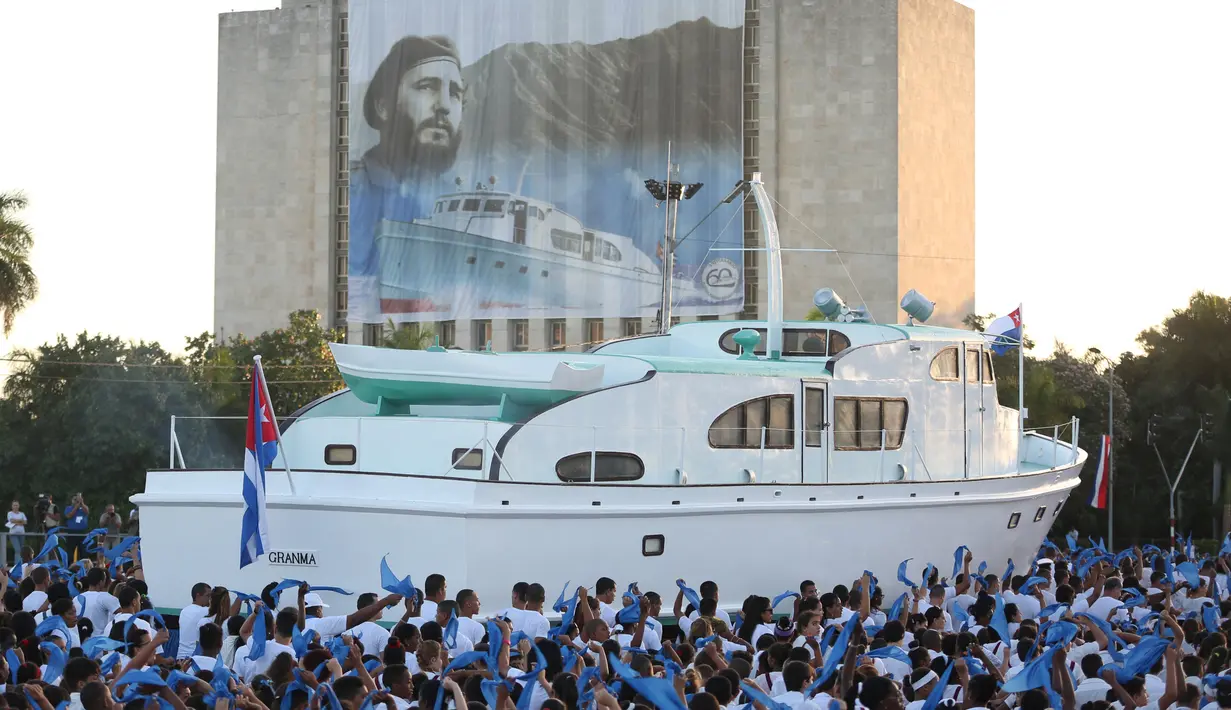 Sebuah replika dari kapal pesiar Granma melintasi spanduk almarhum Presiden Kuba, Fidel Castro yang dipajang selama peringatan Hari Angkatan Bersenjata di Havana, Kuba, Senin (2/1). (Reuters/Desmond Boylan /Pool)