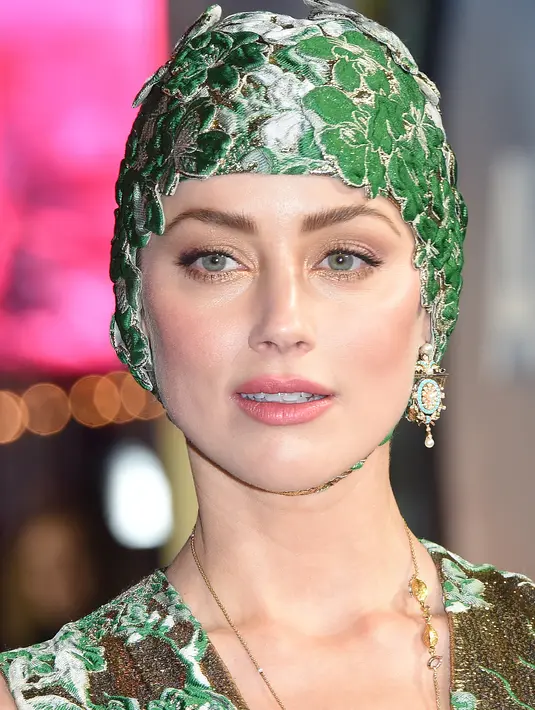 Aktris cantik Amber Heard berpose untuk fotografer setibanya menghadiri premier dunia film 'Aquaman' di London, Senin (26/11). Amber Heard memadukan penampilannya dengan topi renang bernuansa hijau dengan ornamen bunga. (Anthony HARVEY / AFP)