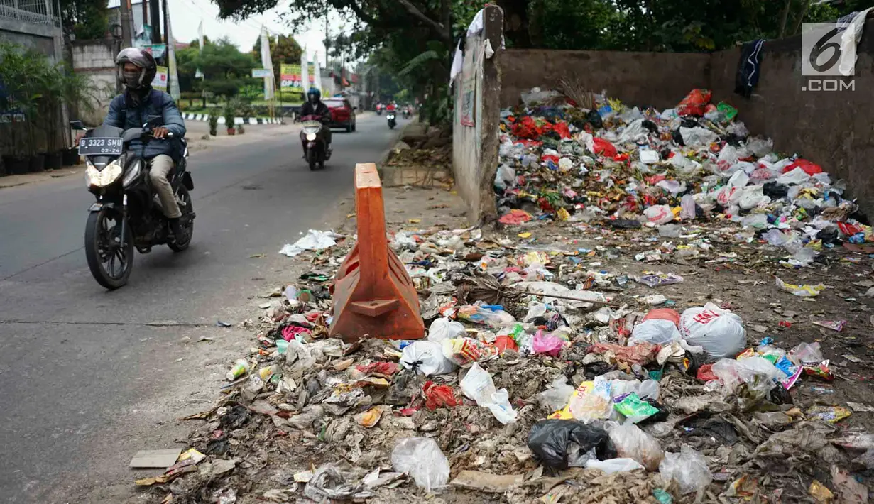 Pengendara melintasi tumpukan sampah rumah tangga di Jalan Raya Tanah Baru kawasan Depok, Jawa Barat, Rabu (15/5/2019). Kurangnya tempat penampungan membuat warga terpaksa membuang sampah di lokasi tersebut, meskipun menimbulkan bau tidak sedap serta mengotori jalan. (Liputan6.com/Immanuel Antonius)