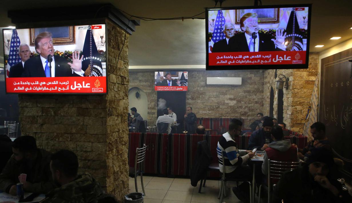 Warga Palestina berada di kafe di kota Ramallah di Tepi Barat saat sebuah siaran televisi menayangkan pidato Presiden AS, Donald Trump mengumumkan AS mengakui Yerusalem sebagai ibu kota Israel (6/12). (AFP Photo/Abbas Momani)