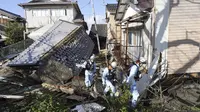 Petugas pemadam kebakaran berjalan melewati rumah-rumah yang roboh akibat gempa bumi di Suzu, prefektur Ishikawa, Jepang, Kamis (4/1/2024). (Kyodo News via AP)