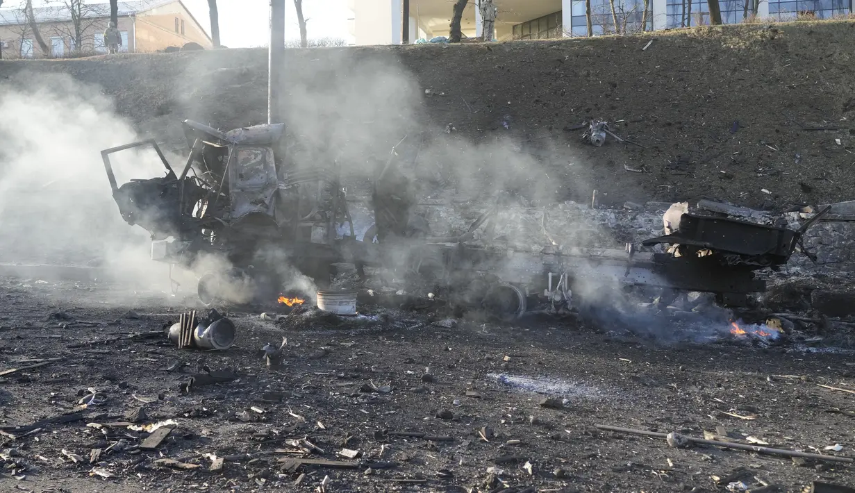 Puing-puing truk militer yang terbakar terlihat di jalan di Kiev, Ukraina, Sabtu (26/2/2022). Pasukan Rusia menyerbu ke arah ibu kota Ukraina pada Sabtu (26/2), dan pertempuran jalanan pecah saat pejabat kota mendesak penduduk untuk berlindung. (AP Photo/Efrem Lukatsky)