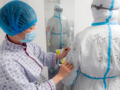 Petugas medis Rumah Sakit Afiliasi Universitas Qingdao memeriksa baju pelindung rekannya di Rumah Sakit Tongji cabang Guanggu di Wuhan, 20 Februari 2020. Beberapa langkah pencegahan dilakukan secara ketat selama dan sesudah jam kerja oleh pekerja medis untuk melawan virus corona. (Xinhua/Cai Yang)