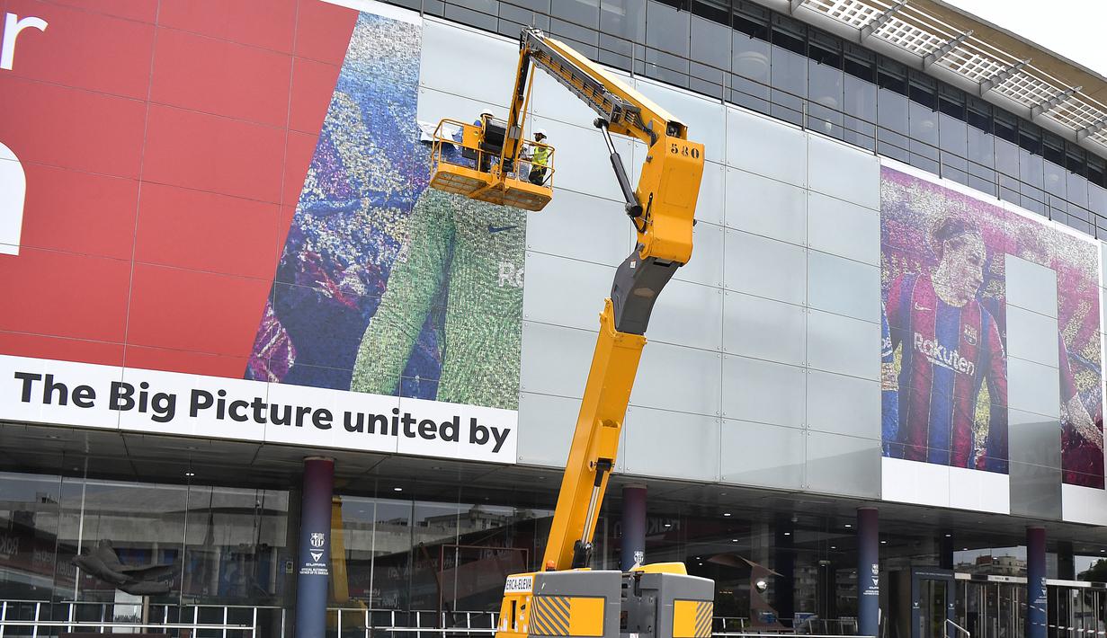 Pekerja menghapus poster yang menampilkan pemain depan Barcelona asal Argentina Lionel Messi di stadion Camp Nou di Barcelona (10/8/2021). Para pendukung PSG berharap untuk melihat pemain asal Argentina itu bergabung ke klub milik Qatar setelah hengkang dari Barcelona. (AFP/ Pau Barrena)