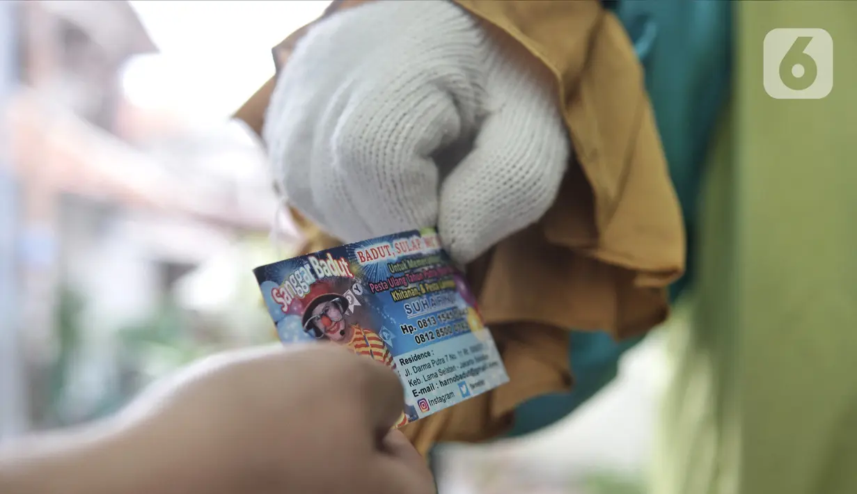 Suharno membagikan kartu nama ke warga usai tampil sebagai badut. Meskipun memiliki pekerjaan sampingan ojek online, Suharno lebih mencintai profesi badut panggilan, menurutnya menjadi suatu kebanggaan dan dapat menghibur diri ketika aksinya mampu menghibur anak-anak. (Merdeka.com/Iqbal S Nugroho)