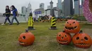 Orang-orang yang memakai masker untuk mencegah penyebaran virus corona, berjalan melewati dekorasi Halloween di sebuah taman di Hong Kong, Rabu (27/10/2021). (AP Photo/Vincent Yu)