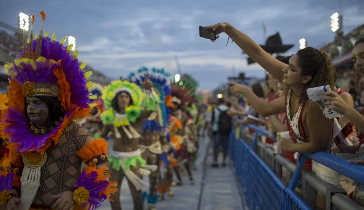 Seorang pengunjung mengambil gambar dengan ponselnya saat Karnaval Samba di Sambadrome, Rio de Janeiro, Brasil, Senin (27/2). Karnaval Samba dimeriahkan oleh hampir seluruh sekolah samba di Brasil. (AP Photo / Mauro Pimentel)