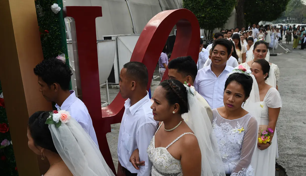 Sejumlah pasangan tiba mengikuti pernikahan massal sebagai bagian dari perayaan Hari Valentine di Manila, Filipina (14/2). Sekitar 200 pasangan dilaporkan ikut serta dalam acara tersebut. (AFP Photo/Ted Aljibe)