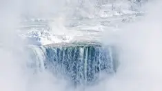 Es dan air mengalir di tepi Horseshoe Falls dari Air Terjun Niagara di Ontario, Kanada, Kamis (31/1). Cuaca dingin yang melanda Amerika Serikat (AS) membuat sebagian Air Terjun Niagara membeku. (Tara Walton/The Canadian Press via AP)