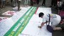 Warga membubuhkan tanda tangan pada spanduk saat Gerakan Kebajikan Pancasila meggelar aksi Pemilu Gembira Melawan Hoax di kawasan Car Free Day (CFD) Bundaran HI, Jakarta, Minggu (3/1). (Liputan6.com/Faizal Fanani)