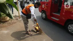 Pelanggar PSSB dihukum menyapu jalanan di Kawasan Kalisari, Pasar Rebo, Jakarta Timur, Kamis (3/9/2020). Warga Kelurahan Pasar Rebo yang kedapatan keluar rumah tanpa menggunakan masker diberikan pilihan hukuman, salah satunya dimasukkan ke dalam peti mati selama 1 menit. (Liputan6.com/Herman Zakhari