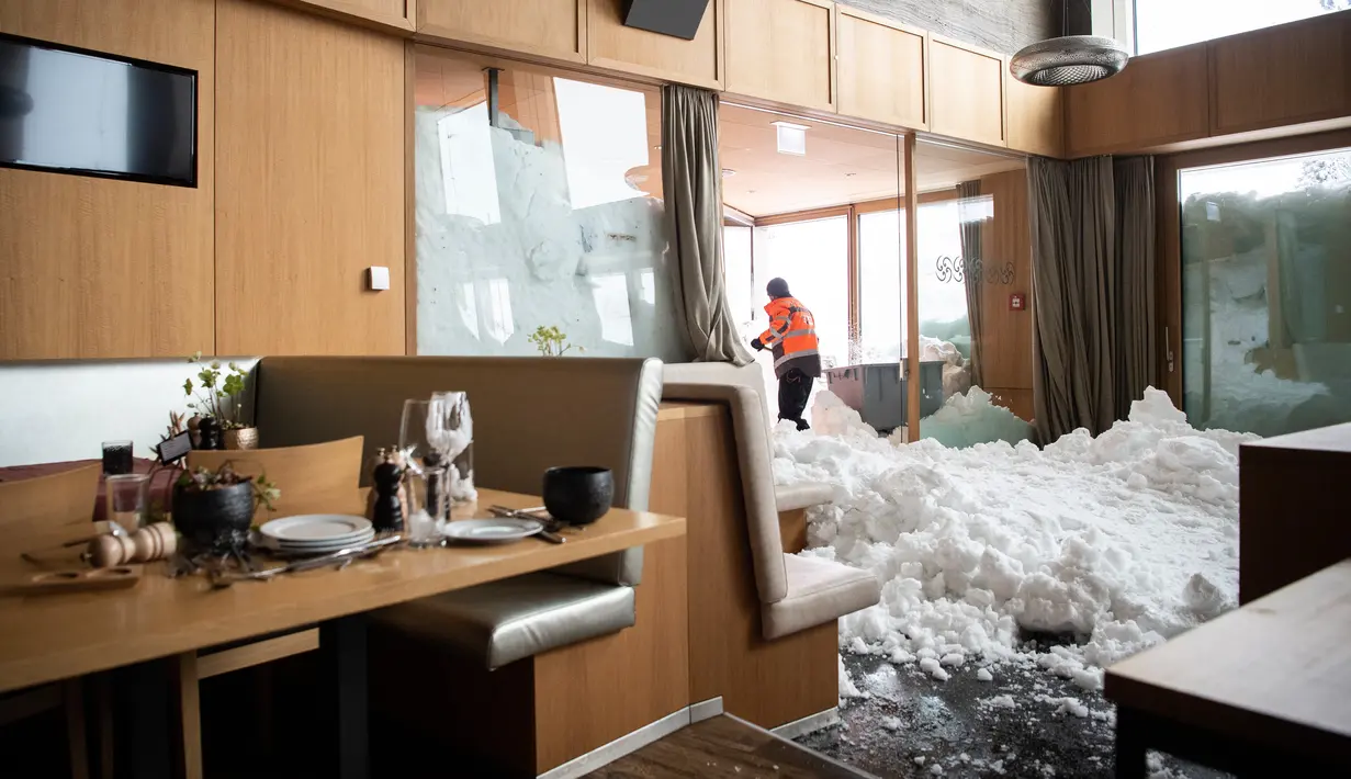 Petugas membersihkan longsoran salju yang masuk ke dalam Hotel Saentis di Schwaegalp, Swiss, Jumat (11/1). (Gian Ehrenzeller/Keystone via AP)