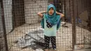 Seorang gadis berpose depan salah satu toko yang tutup di Kamp al-Hol, Provinsi Hasakeh, Suriah, Sabtu (1/5/2021). Pejabat Kurdi mengatakan keamanan telah meningkat di kamp yang luas di timur laut Suriah, tetapi kekhawatiran berkembang dari wabah COVID-19 di fasilitas itu. (AP Photo/Baderkhan Ahmad)