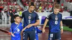 Pemain Jepang, Hidemasa Morita (kedua kiri) menuntun anak kecil yang ditugaskan sebagai player escort dalam pertandingan lanjutan putaran ketiga Grup C Kualifikasi Piala Dunia 2026 melawan Timnas Indonesia di Stadion Utama Gelora Bung Karno (SUGBK), Senayan, Jakarta, Jumat (15/11/2024). (Bola.com/Bagaskara Lazuardi)