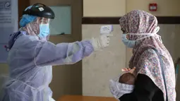 Seorang wanita Palestina menjalani pengecekan suhu tubuh di sebuah pusat layanan kesehatan saat pemberlakuan lockdown, Kota Rafah, Jalur Gaza, 9 September 2020. (Xinhua/Khaled Omar)