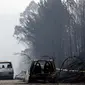 Bangkai mobil yang hangus di tengah jalan antara Castanheira de Pera dan Figueiro dos Vinhos, Portugal, Minggu (18/6). Ratusan mobil pemadam kebakaran dikerahkan guna mengatasi kobaran api yang telah menyebar di berbagai area itu (AP Photo/Armando Franca)