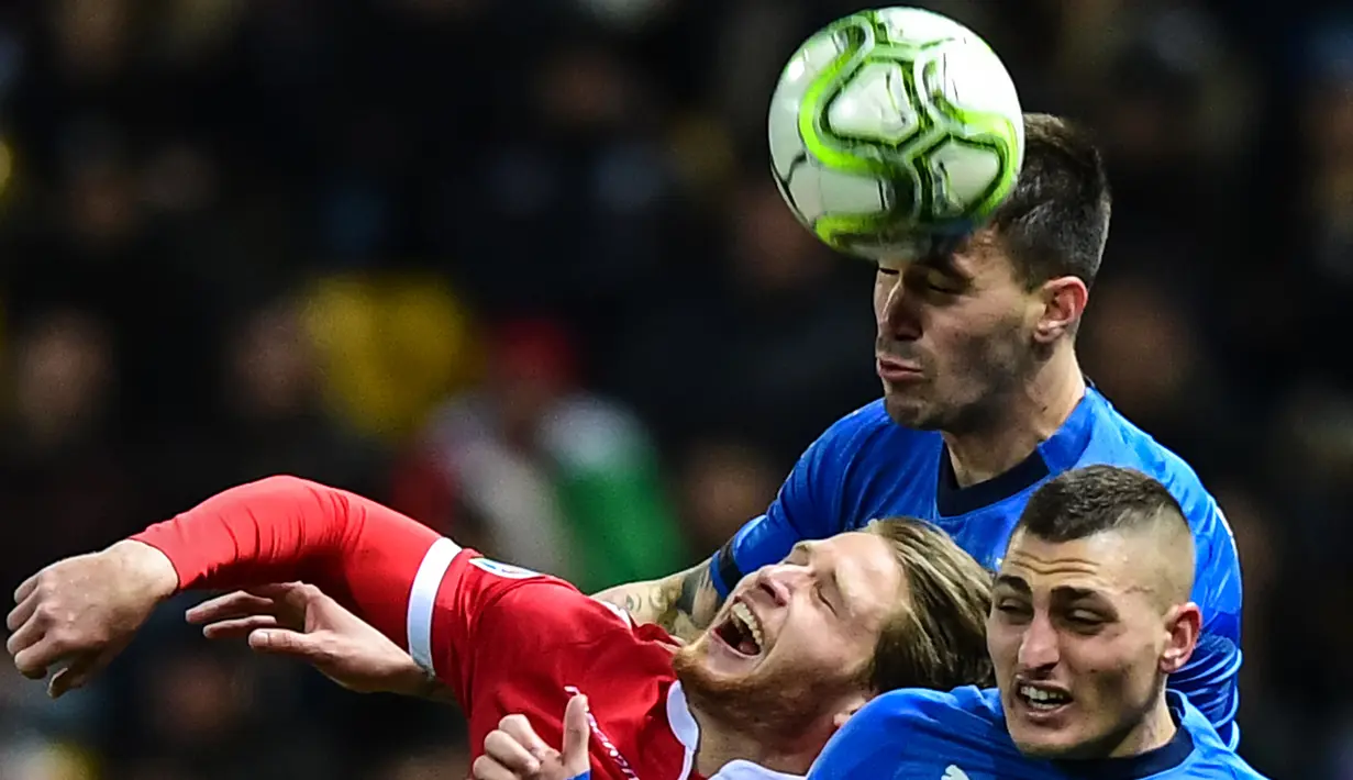 Striker Liechtenstein, Nicolas Hasler, duel udara dengan pemain Italia, Alessio Romagnoli dan Marco Verratti pada laga Kualifikasi Piala Eropa 2020 di Stadion Ennio-Tardini, Selasa (26/3). Italia menang 6-0 atas Liechtenstein. (AFP/Miguel Medina)