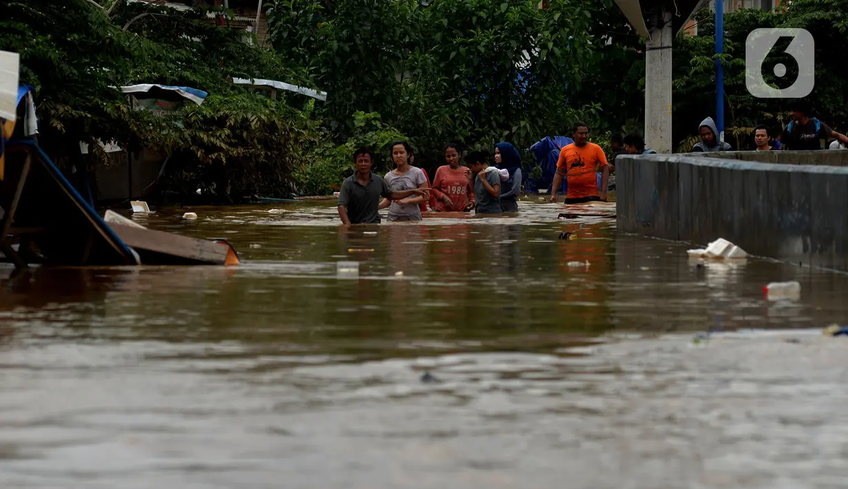 Warga melewati banjir yang menggenangi Jalan Jatinegara Barat, Jakarta, Kamis (2/1/2020). Hujan yang terjadi kemarin malam membuat Kali Ciliwung meluap ke jalan. (merdeka.com/Imam Buhori)