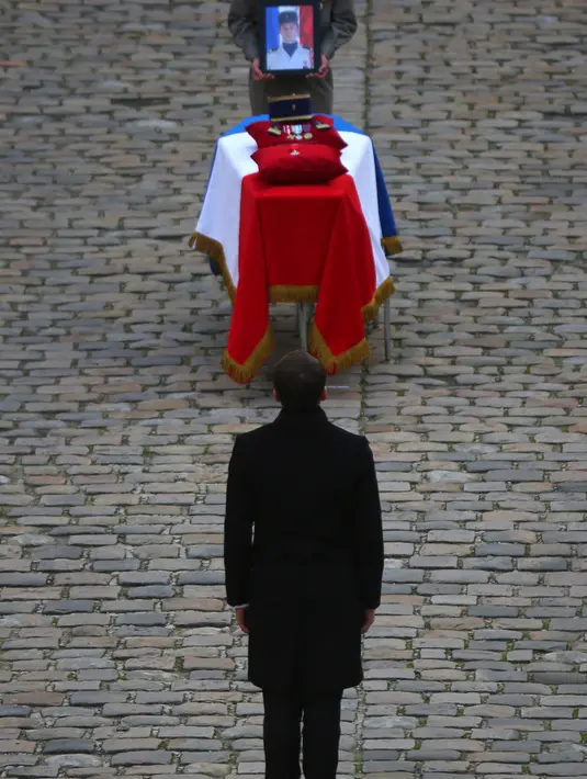 Presiden Prancis Emmanuel Macron berdiri dekat peti jenazah salah satu dari 13 tentara Prancis yang tewas dalam kecelakaan helikopter di Mali, Paris, Senin (2/12/2019). Sebanyak 13 tentara tewas setelah dua helikopter bertabrakan dalam operasi melawan miltan di Mali. (AP Photo/Rafael Yaghobzadeh)