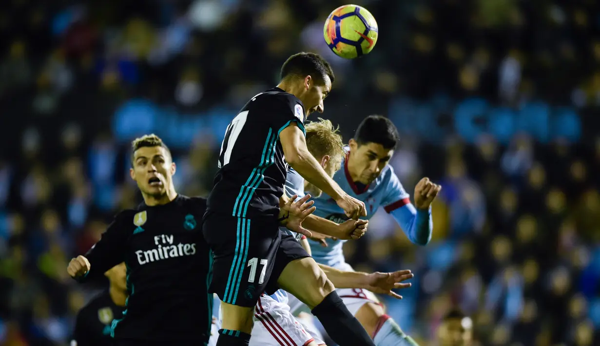 Gelandang Real Madrid Lucas Vazquez menyundul bola pada pertandingan pekan ke-18 La Liga kontra Celta Vigo di Estadio de Balaidos, Minggu (7/1). Sempat unggul berkat dua gol Gareth Bale, Madrid akhirnya harus puas dengan skor akhir 2-2. (MIGUEL RIOPA/AFP)