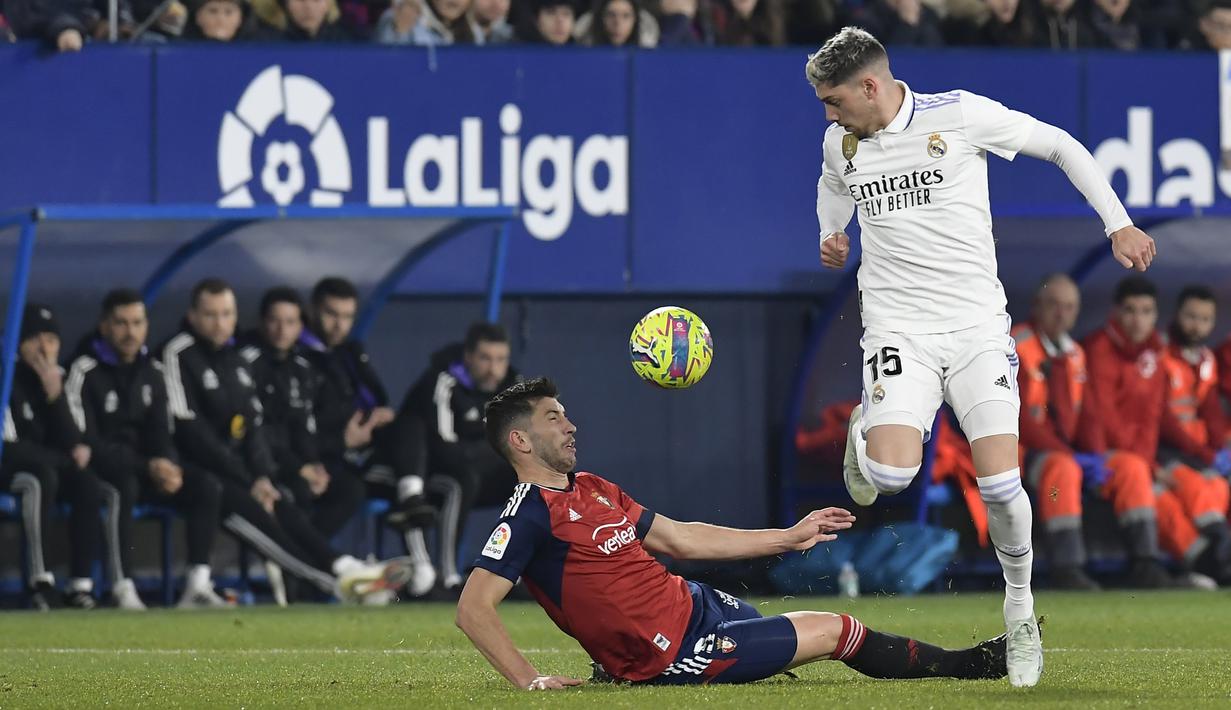 <p>Gelandang Real Madrid, Federico Valverde berusaha melewati pemain Osasuna, David Garcia selama pertandingan sepak bola La Liga Spanyol antara Osasuna dan Real Madrid di stadion El Sadar di Pamplona, Spanyol, Sabtu, 18 Februari 2023. (AP Photo/Alvaro Barrientos)</p>