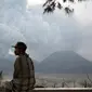 Seorang warga setempat duduk di bangku kayu sambil melihat Gunung Bromo yang sedang erupsi di Ngadisari, Probolinggo, Jawa Timur, Selasa (5/1/2016). (REUTERS/Darren Whiteside)