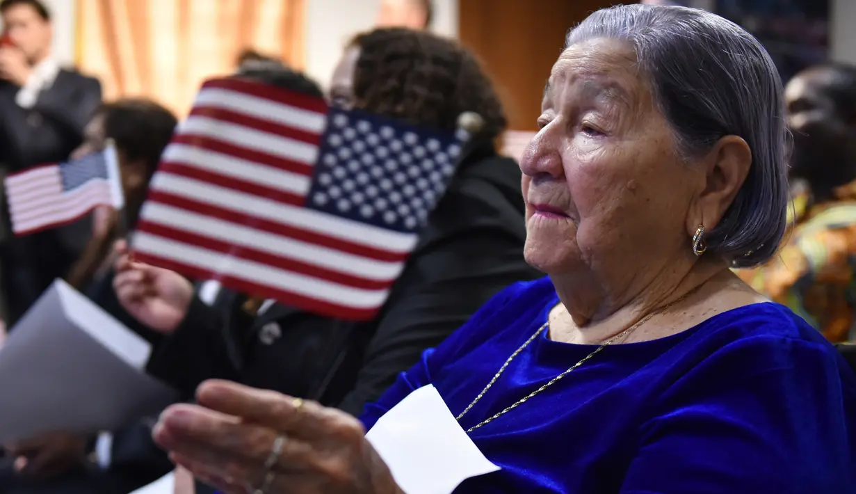 Maria Valles Bonilla melambaikan bendera AS selama upacara naturalisasi di kantor Citizenship and Immigration Services AS (USCIS) di Fairfax, Virginia, 6 November 2018. Nenek 106 tahun itu resmi menjadi warga negara Amerika Serikat. (MANDEL NGAN/AFP)