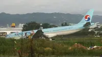 Pesawat Korean Air yang rusak masih terjebak di rerumputan setelah melewati landasan pacu di Bandara Internasional Mactan-Cebu di Cebu, Filipina tengah Senin pagi 24 Oktober 2022. (AP/Juan Carlo De Vela)