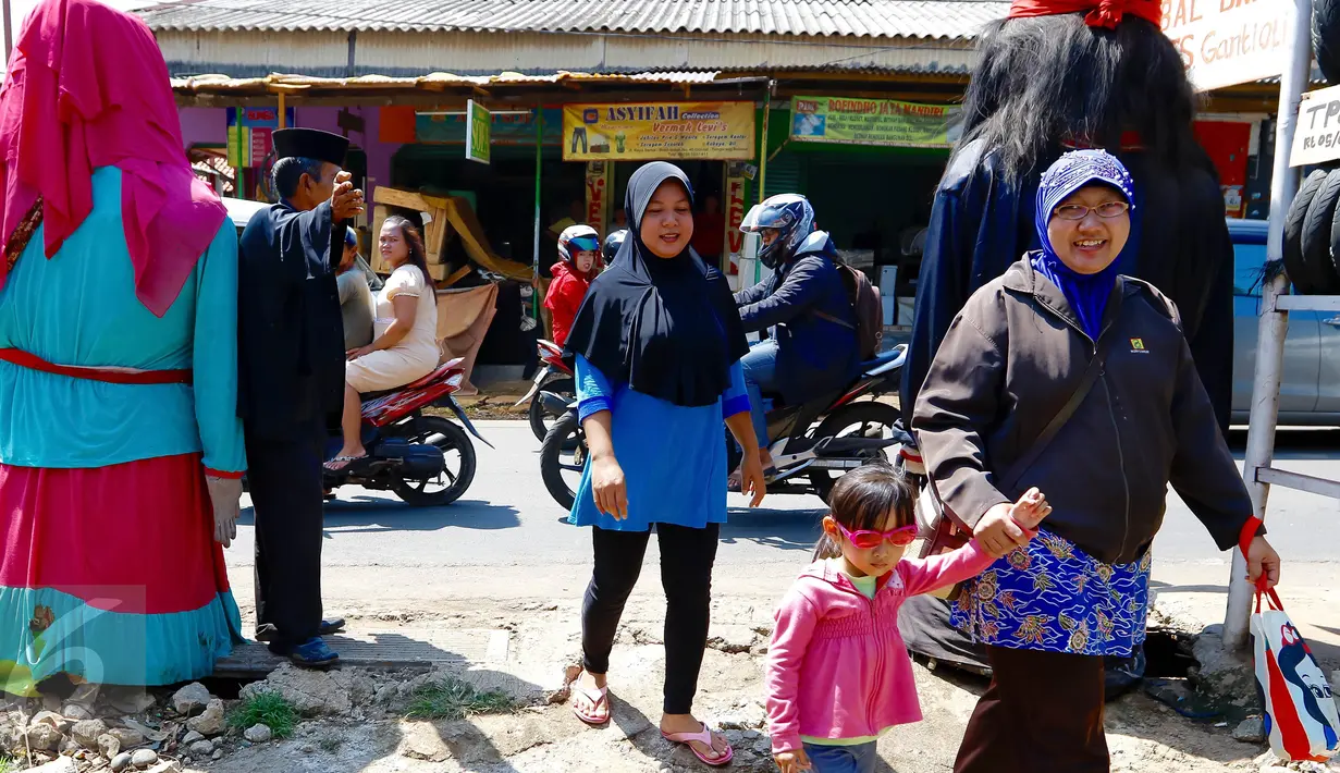 Boneka ondel-ondel tampak terpajang di pintu masuk TPS 13 Kelurahan Serua, Tangerang Selatan, Rabu (9/12). Jutaan warga Tangsel mengikuti hak suaranya untuk memilih 3 pasangan calon dalam Pilkada Serentak. (Liputan6.com/Fery Pradolo)