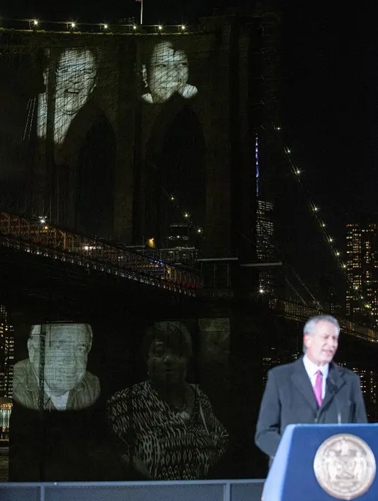 Wali Kota New York Bill De Blasio berbicara saat gambar korban diproyeksikan pada Jembatan Brooklyn selama Hari Peringatan COVID-19 di Brooklyn, New York, Amerika Serikat, 14 Maret 2021. Kendati pandemi, De Blasio tetap meminta warga New York untuk mengingat saat-saat indah. (Kena Betancur/AFP)