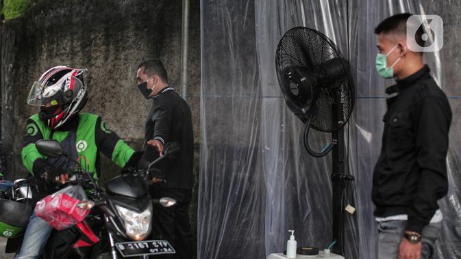 Pengendara sepeda motor disemprot cairan disinfektan saat akan memasuki pemukiman warga di kawasan H. Gari, Pesanggrahan, Jakarta, Jumat (3/4/2020). Penyemprotan secara swadaya tersebut dilakukan warga untuk mencegah penyebaran virus corona COVID-19. (Liputan6.com/Johan Tallo)