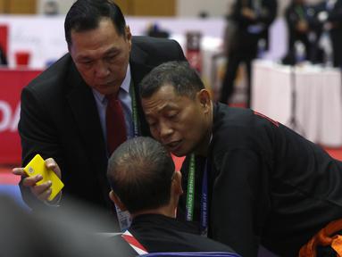 Ketua Harian PB Ikatan Pencak Silat Indonesia (IPSI) yang juga menjabat sebagai Ketua Eksekutif Persekutuan Pencak Silat Antarabangsa (Persilat), Benny Sumarsono (kiri) menghampiri dan terlibat argumentasi dengan pelatih pencak silat Indonesia, Bondan (tengah). (Bola.com/Ikhwan Yanuar)