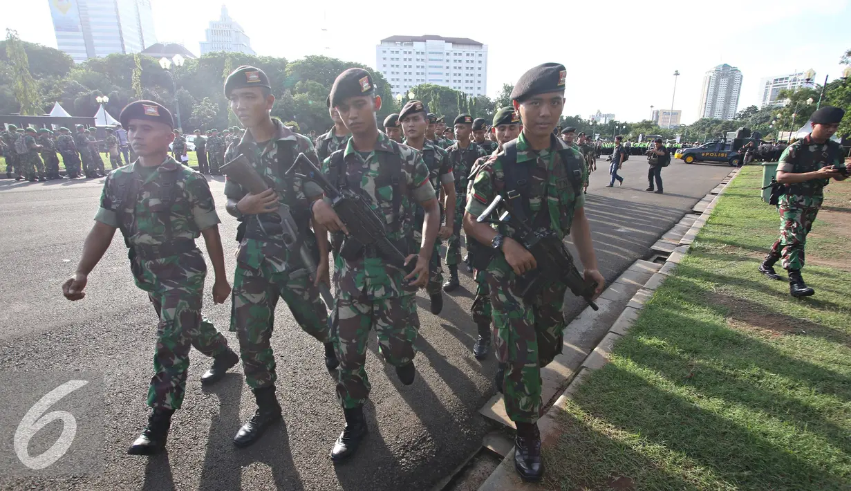 Petugas TNI bersiap untuk mengikuti apel gabungan di Monas, Jakarta, Kamis (31/12). Sebanyak 1300 personel gabungan yang terdiri dari polisi, TNI, Pol PP, dan Pramuka dikerahkan untuk mengamankan perayaan malam tahun baru. (Liputan6.com/Immanuel Antonius)