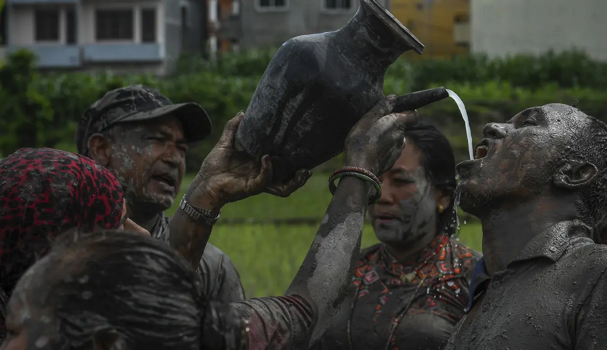 Seorang petani minum anggur beras dari gelas tanah di sawah selama "Hari Padi Nasional", yang menandai dimulainya musim tanam padi tahunan, di desa Tokha di pinggiran Kathmandu, Nepal, Selasa (29/6/2021). (AFP/Prakash Mathema)