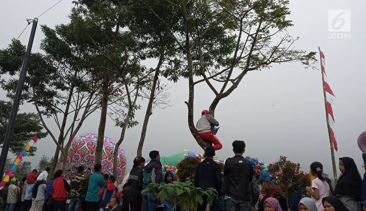 Sejumlah warga melihat balon udara dinaikan di Lapangan Pagerejo, Kertek, Kabupaten Wonosobo,  Sabtu (15/6/2019). Festival ini untuk memeriahkan syawalan dan wujud syukur warga yang hidup di lereng gunung sindoro dan sumbing. (Liputan6.com/Gholib)