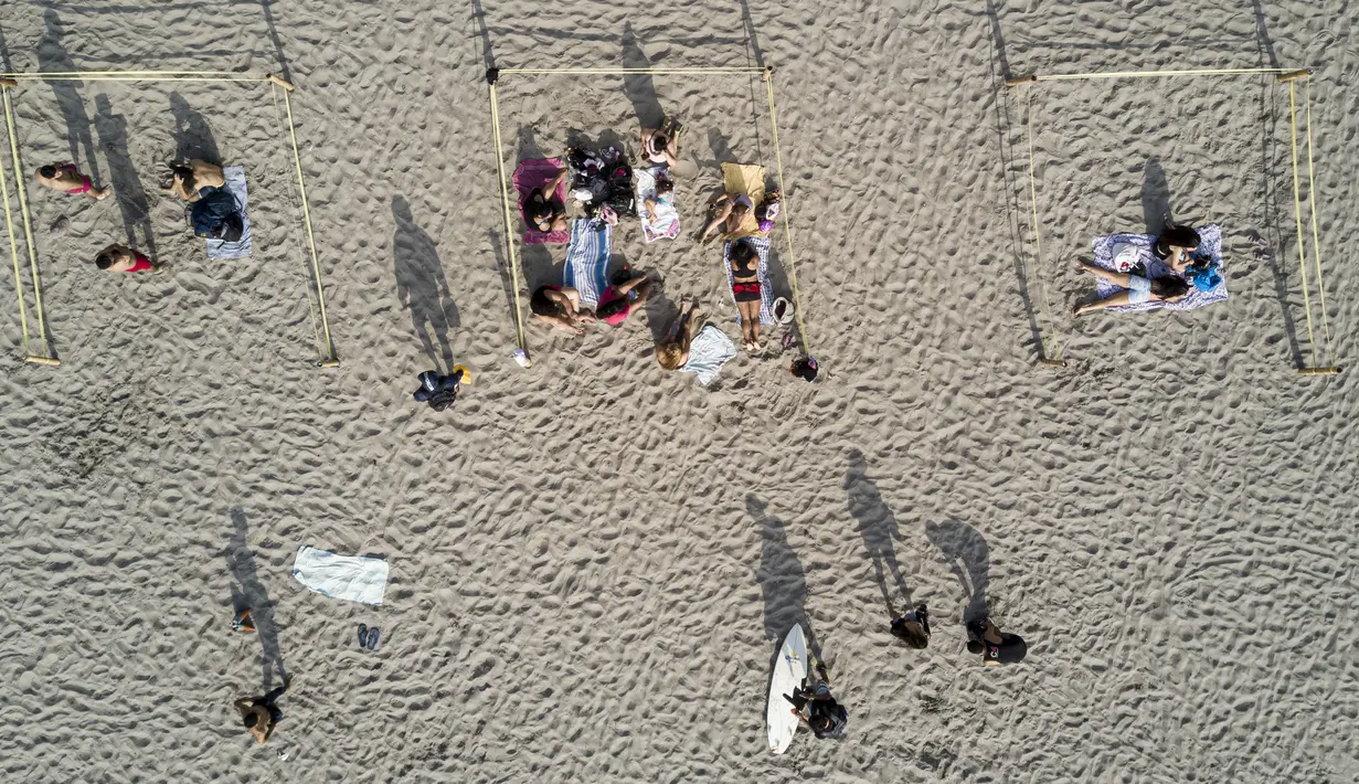 Para pengunjung berjemur dalam pembatas untuk menghindari keramaian di tengah pandemi COVID-19 di Pantai Lima, Peru, Rabu (21/12/2021). Di pantai-pantai populer di Lima, pihak berwenang memutuskan membuat pembatas untuk mencegah kerumunan pengunjung. (Ernesto BENAVIDES/AFP)