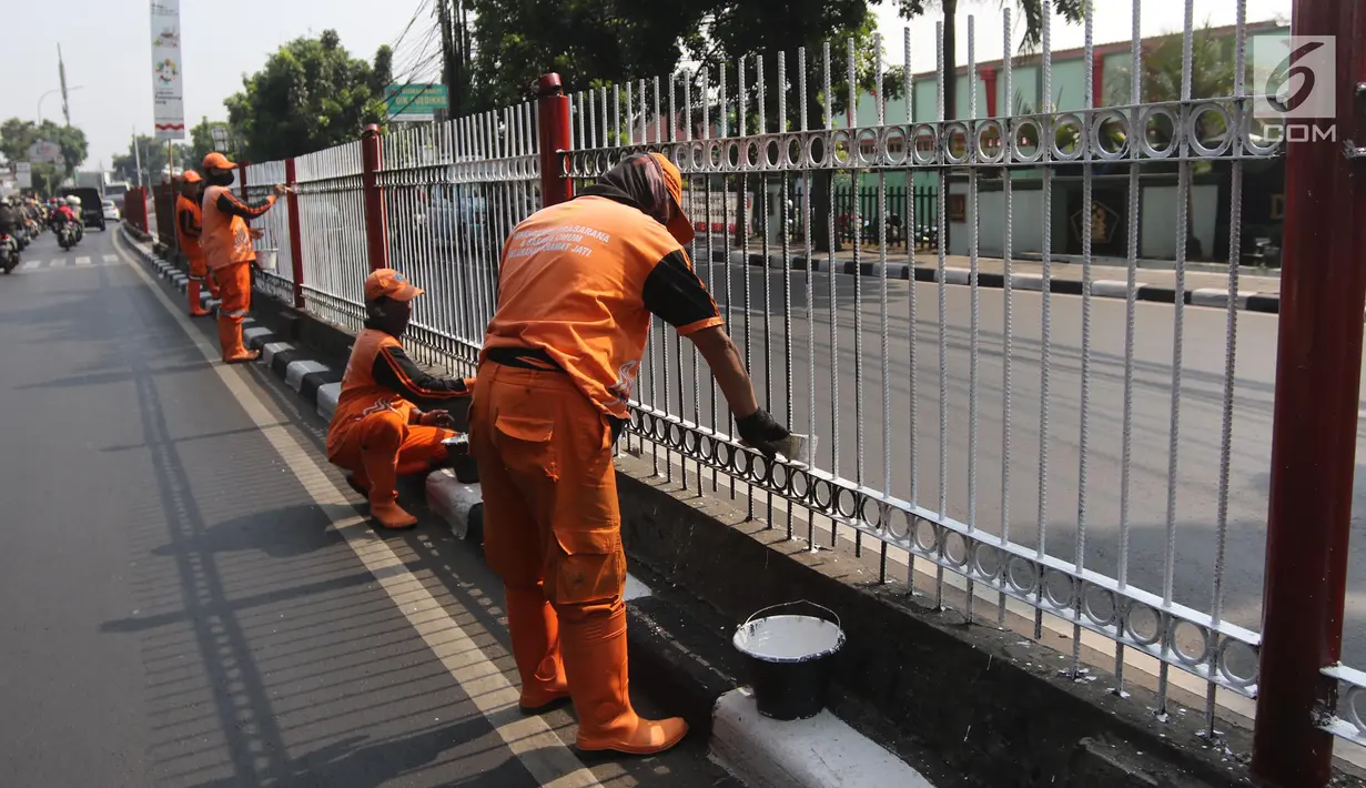 Petugas PPSU Kelurahan Kramat Jati mengecat ulang pagar pembatas Jalan Raya Bogor, Jakarta, Selasa (17/7). Pengecatan sebagai upaya perawatan berkala terhadap sarana dan prasarana yang sudah mulai kehilangan fungsi atau rusak. (Liputan6.com/Arya Manggala)