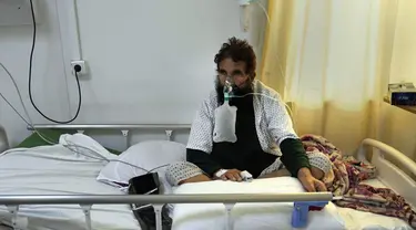 Pasien COVID-19 duduk di tempat tidur di ICU Rumah Sakit Penyakit Menular Afganistan-Jepang di Kabul, 7 Februari 2022. Lima dari 38 rumah sakit perawatan COVID yang pernah beroperasi di Afghanistan terpaksa ditutup karena kekurangan dokter, obat-obatan dan bahkan pemanas. (AP Photo/Hussein Malla)