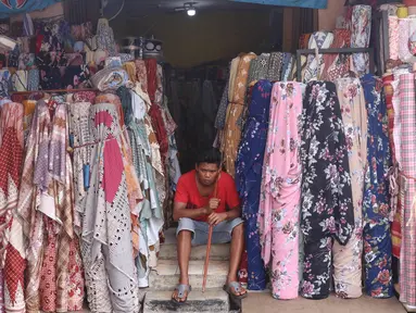 Pekerja menunggu pembeli di salah satu toko di Pasar Cipadu, Tangerang, Selasa (2/3/2021). Pandemi Covid-19 membuat industri tekstil dan pakaian jadi mengalami pertumbuhan negatif 8, 8 persen sepanjang 2020 dengan kinerja ekspor yang berkontraksi 17 persen. (Liputan6.com/Angga Yuniar)