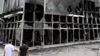 Dua pria melihat fasad Hotel du ville yang hangus dan terbakar di Garges-les-Gonesse, utara Paris, menyusul kerusuhan dua hari setelah seorang remaja 17 tahun ditembak di dada oleh polisi dari jarak dekat di Nanterre, pinggiran barat Paris, pada 29 Juni 2023. (Photo by Bertrand GUAY / AFP)