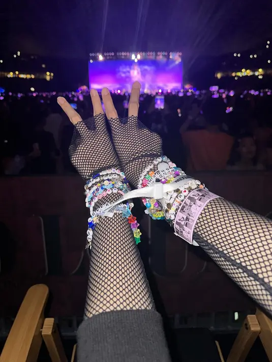 <p>Lisa memamerkan gelangnya di foto pertama dari carousel sambil menunjukkan tanda peace. Dia menikmati konser bersama teman-temannya. (Foto: Instagram/ lalalalisa_m)</p>