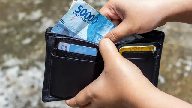 Seseorang Sedang Mengeluarkan Uang Rupiah dari Dompetnya