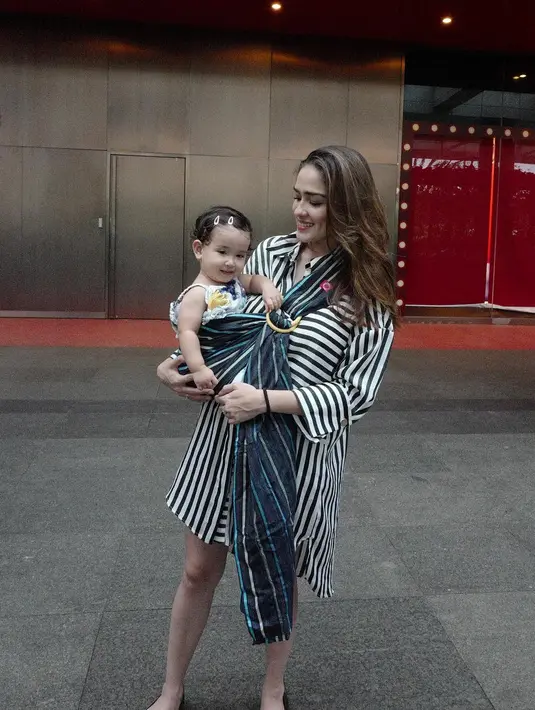 Penampilan Yasmine tidak pudar saat menggendong buah hatinya dengan kain. Ia tampak kece dengan oversized shirtnya yang bermotif garis-garis. Cantik dan seksi, cocok banget untuk menggambarkan Yasmine. (Instagram/yaswildblood)