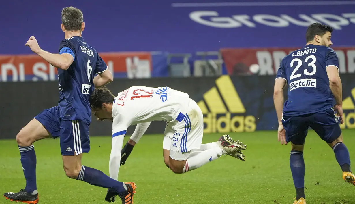 Gelandang Lyon, Lucas Paqueta (tengah) terjatuh di antara dua pemain Bordeaux, Laurent Koscielny (kiri) dan Loris Benito dalam laga lanjutan Liga Prancis 2020/21 pekan ke-22 di Groupama Stadium, Jumat (29/1/2021). Lyon menang 2-1 atas Bordeaux. (AP/Laurent Cipriani)