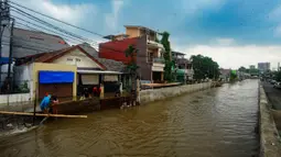 Pekerja membuat penahan tanggul kali sementara sepanjang 20 meter menggunakan papan, karung berisi pasir, dan rangka besi cor untuk mengurangi debit air yang masuk ke pemukiman warga. (merdeka.com/Arie Basuki)