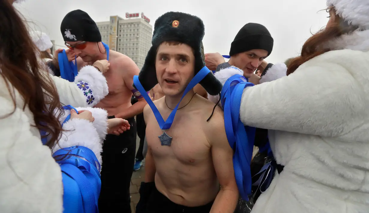 Seorang pria menerima medali setelah mencapai garis finis acara "Real men's race" di Minsk, Belarusia, Kamis (23/2). Ratusan pria bertelanjang dada sambil berlari keliling Kota Minsk untuk memperingati Hari Pertahanan Tanah Air. (AP Photo/Sergei Grits)