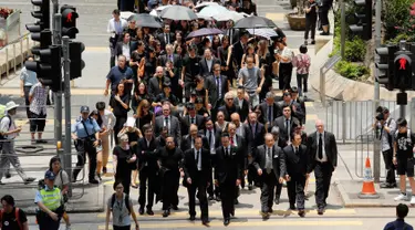 Pengacara menyeberang jalan saat berdemonstrasi di Hong Kong, Rabu (7/8/2019). Ratusan pengacara bergabung dalam barisan massa prodemokrasi menolak RUU Ekstradisi yang kontroversial. (AP Photo/Kin Cheung)