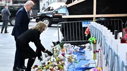 Ibu Negara Jill Biden terlihat meletakkan karangan bunga di lokasi sesaat sebelum keduanya menundukkan kepala untuk mengheningkan cipta. (ROBERTO SCHMIDT/AFP)